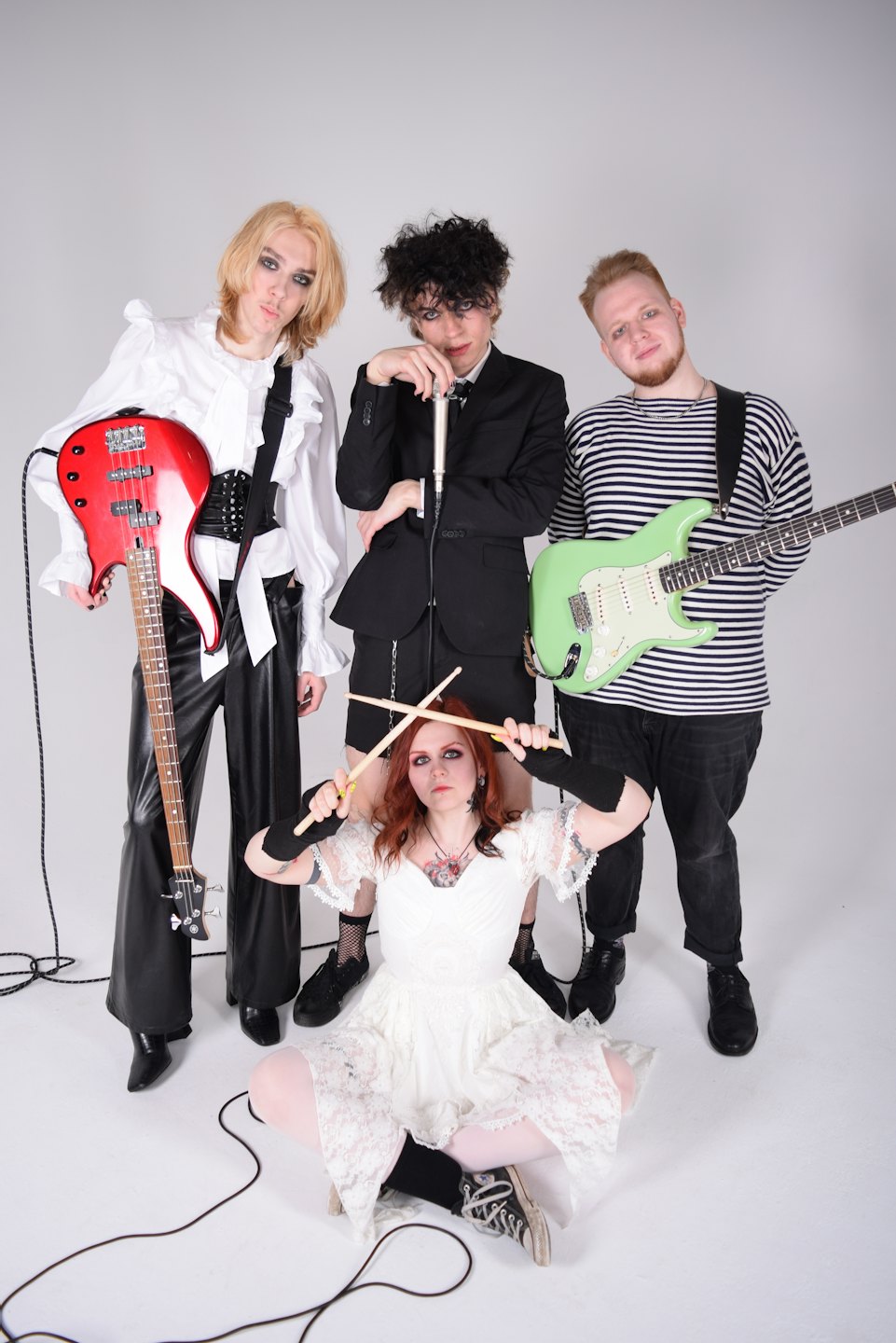 Four young musicians in band attire holding instruments in a studio.