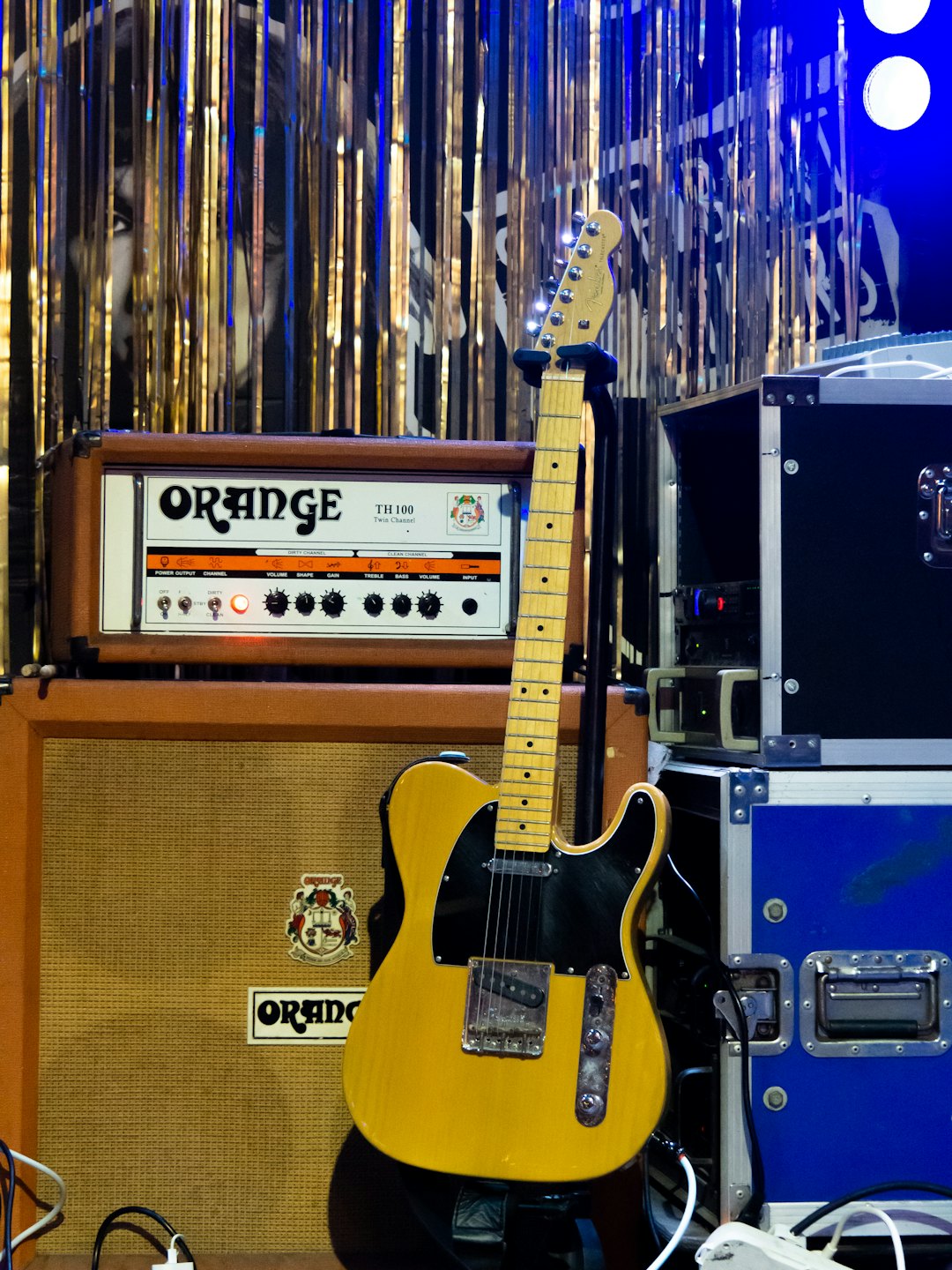 Yellow electric guitar standing in front of a stage amplifier.