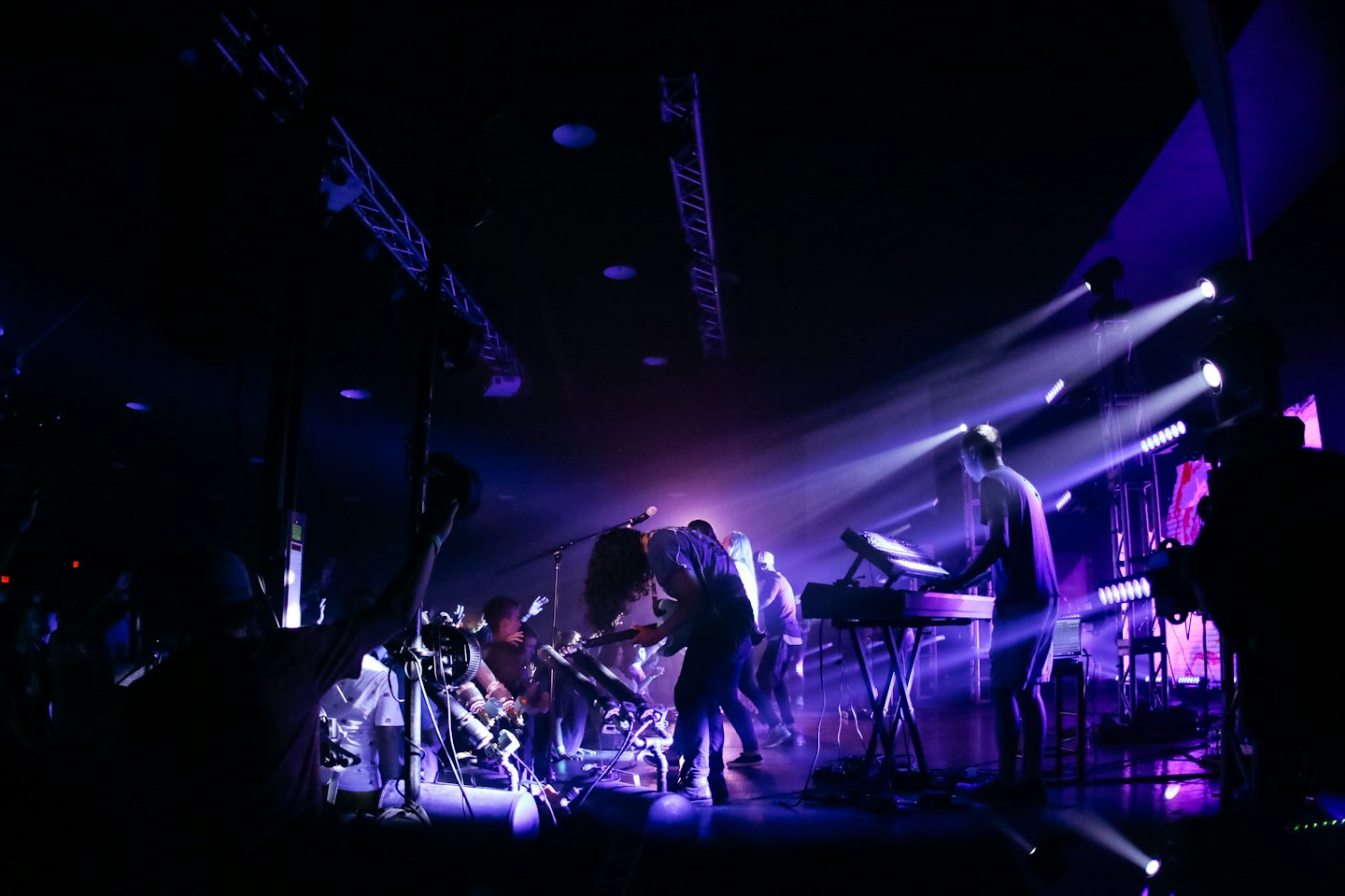 Band members perform music on stage for a cheering crowd.