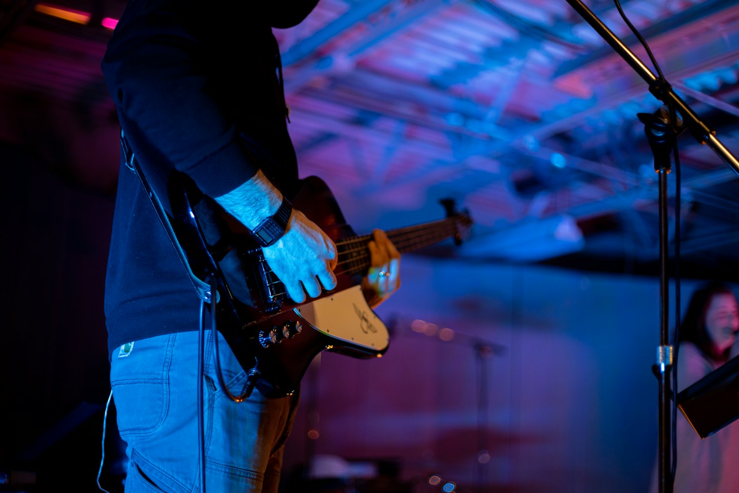 A musician plays an electric bass guitar on stage.